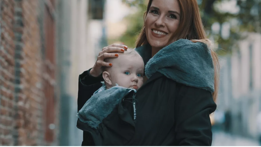 Maman portant son bébé dans un manteau de portage en hiver